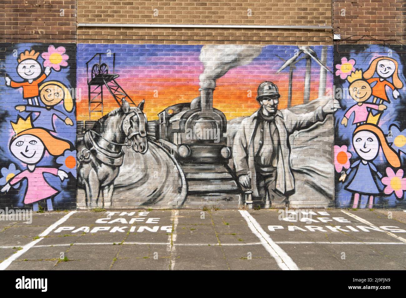 Un murale su un muro nella città di Lynemouth, Northumberland, Regno Unito, racconta la storia della sua industria e cultura - dall'estrazione del carbone alle fattorie eoliche. Foto Stock