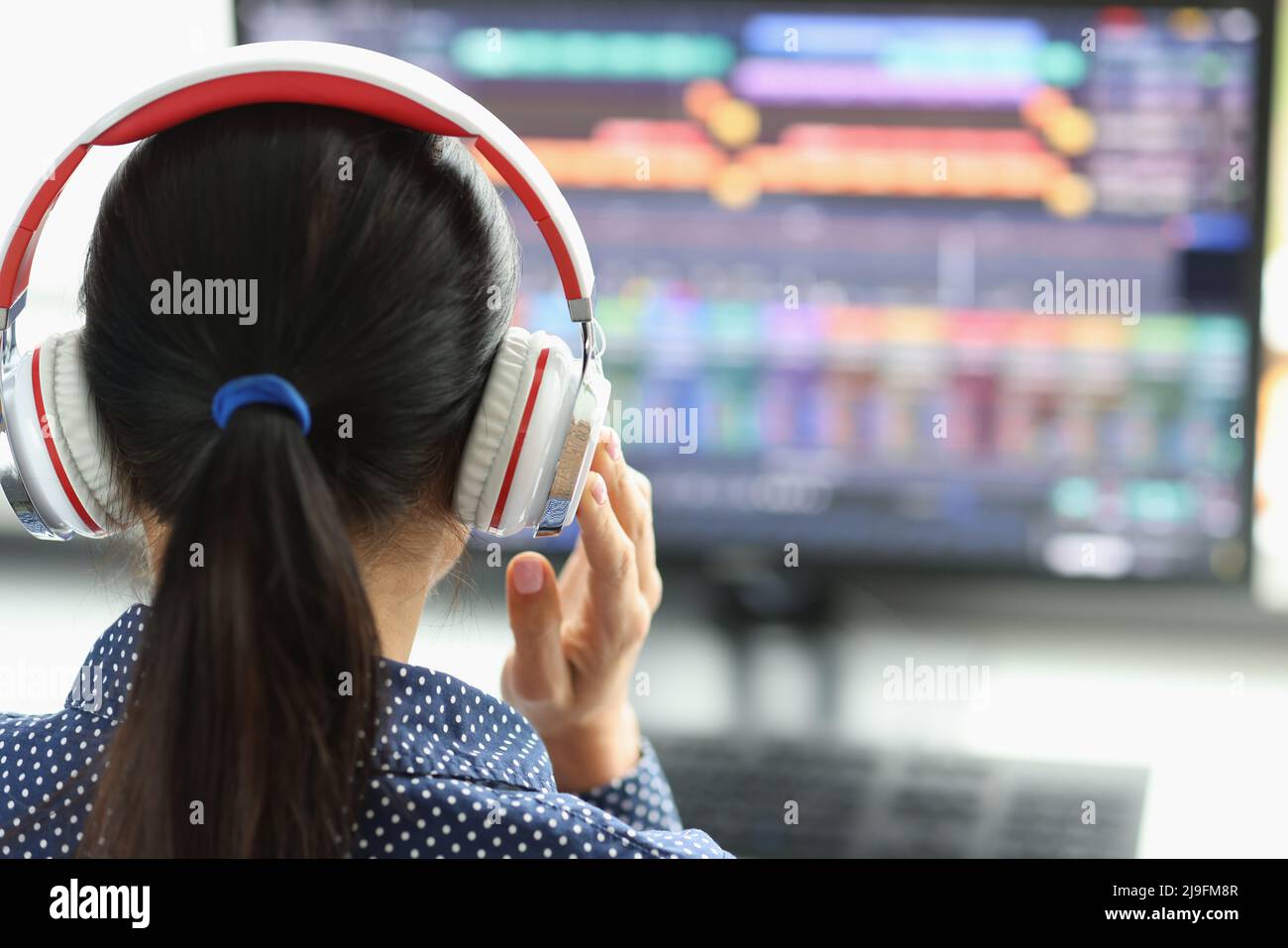 Donna in cuffie di fronte al computer comunica tramite webcam Foto Stock