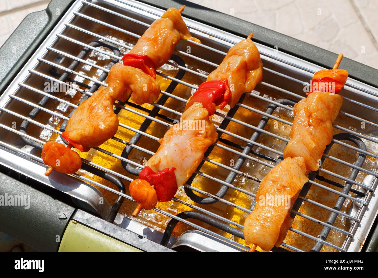 Brocetta di pollo marinata cruda sulla griglia di un barbecue elettrico Foto Stock