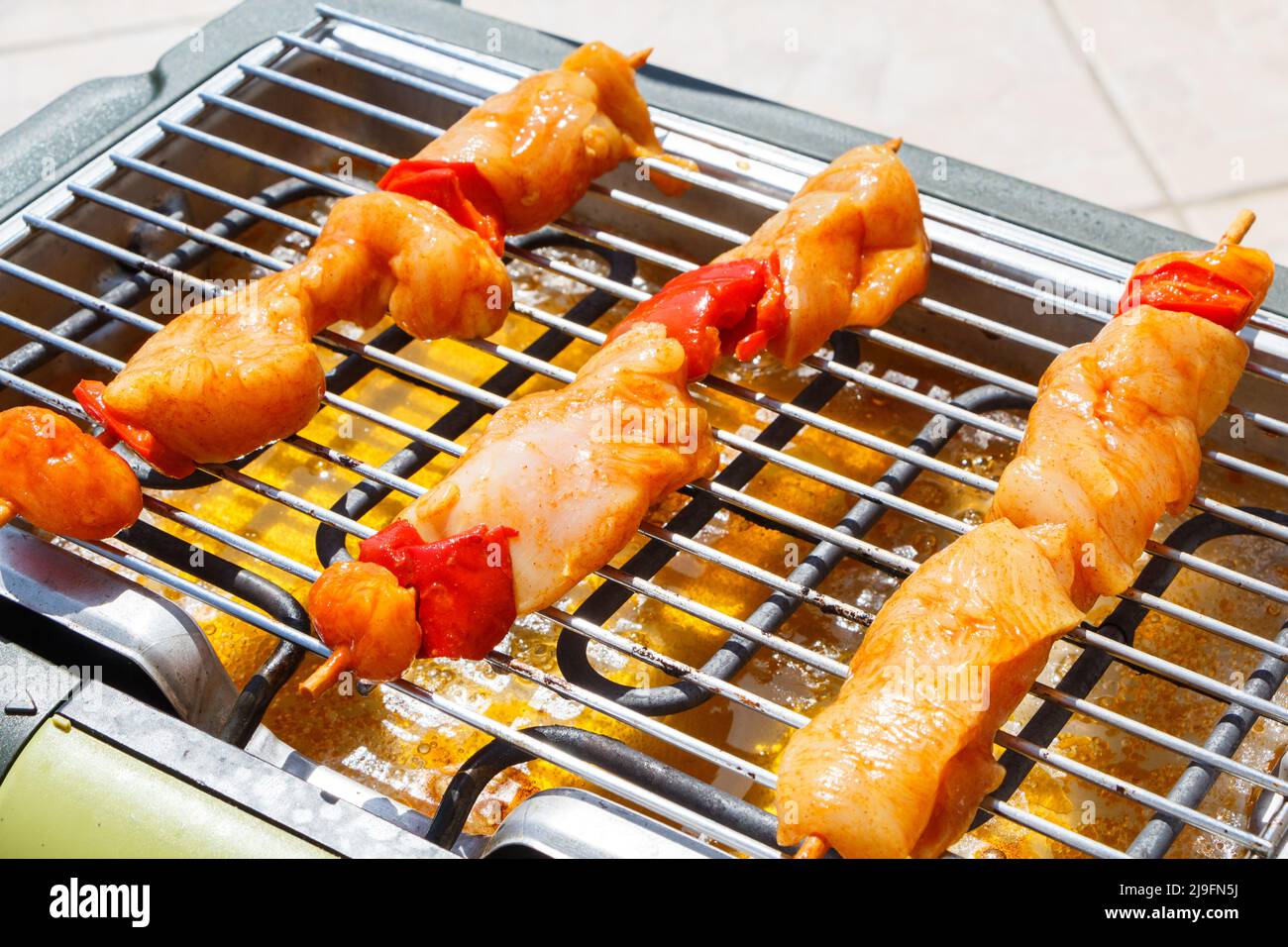 Brochette di pollo marinate sulla griglia di un barbecue elettrico durante l'estate Foto Stock