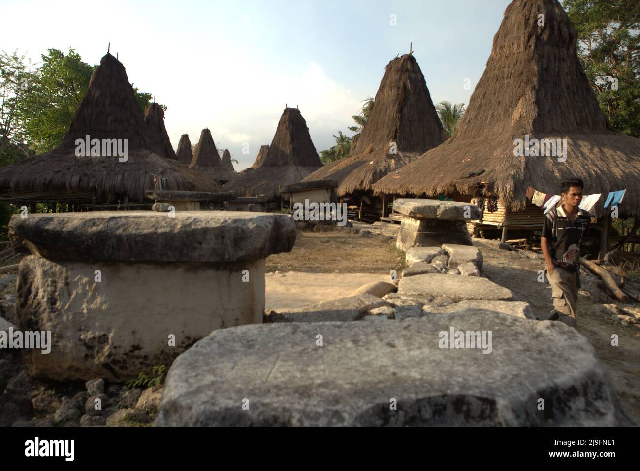 Un uomo che cammina sul lato delle tombe megalitiche nel villaggio tradizionale di Praijing a Tebara, Waikabubak, West Sumba, East Nusa Tenggara, Indonesia. Foto Stock