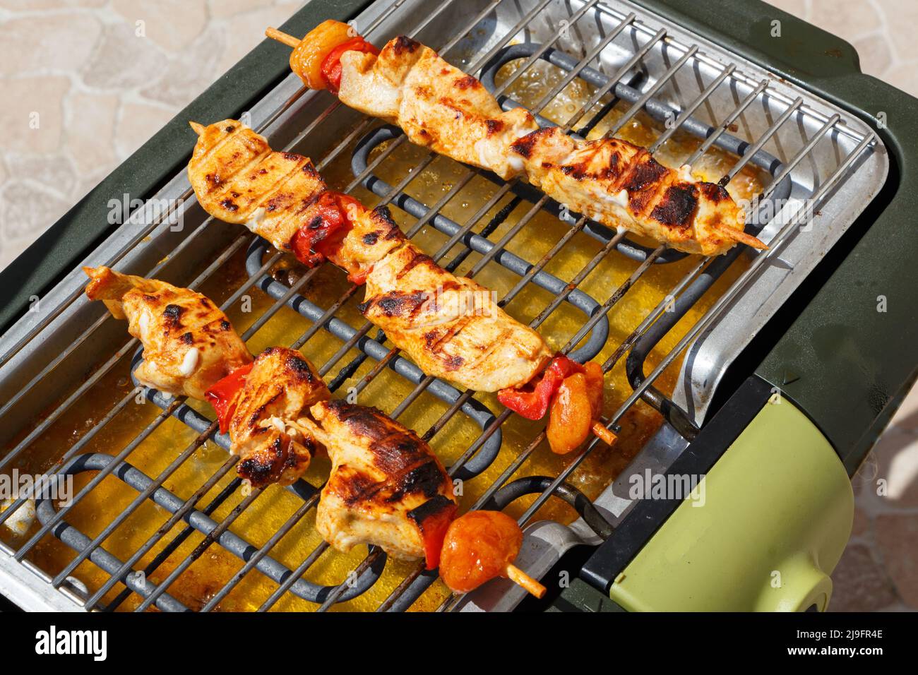 Brochette di pollo marinate sulla griglia di un barbecue elettrico durante l'estate Foto Stock