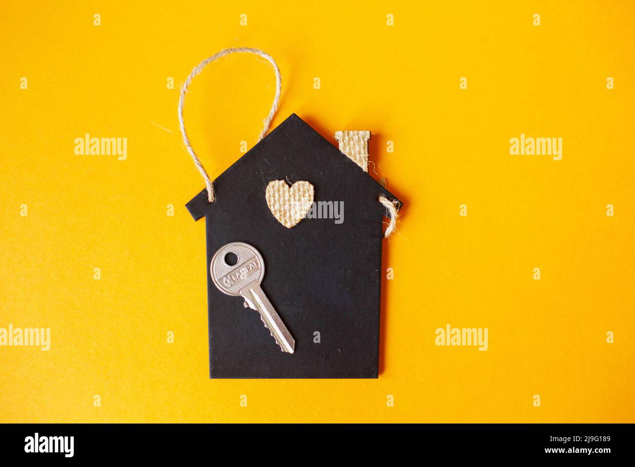 Piccola casa giocattolo con una chiave su sfondo arancione Foto Stock