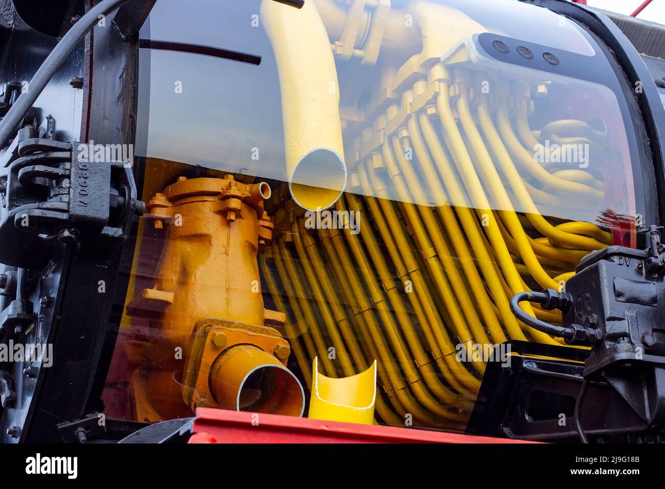 Vecchia locomotiva a vapore retrò nera e rossa presso la stazione ferroviaria con vista su un tubo interno. Vintage treno che rimane sulla ferrovia. Foto Stock