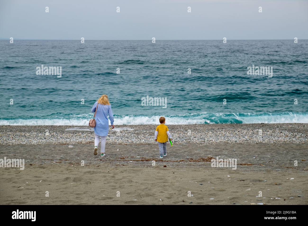 Madre che cammina con suo figlio in spiaggia Foto Stock