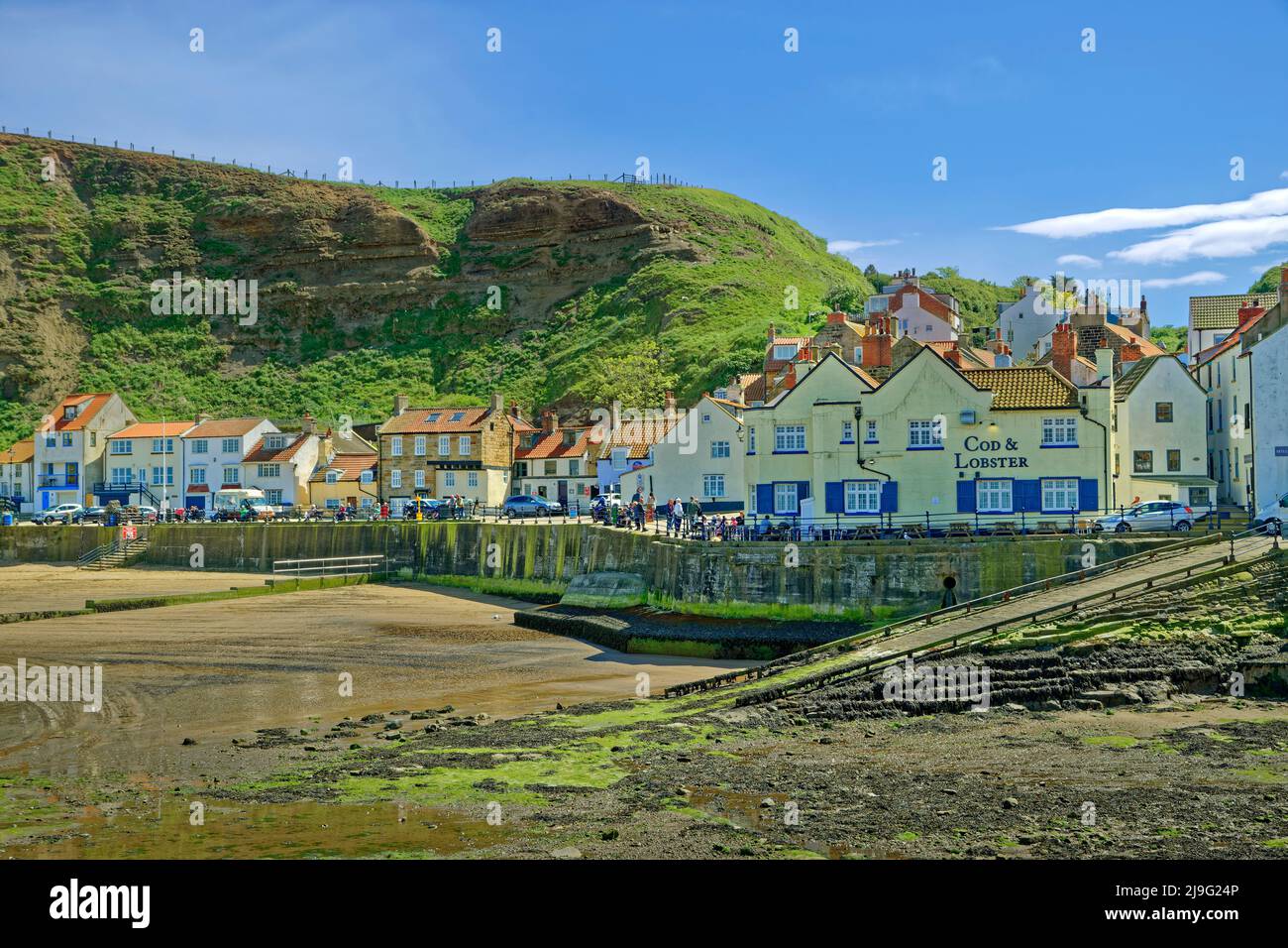 Porto e villaggio con il 'Cod & Lobster' Inn a Staithes, North Yorkshire, Inghilterra. Foto Stock