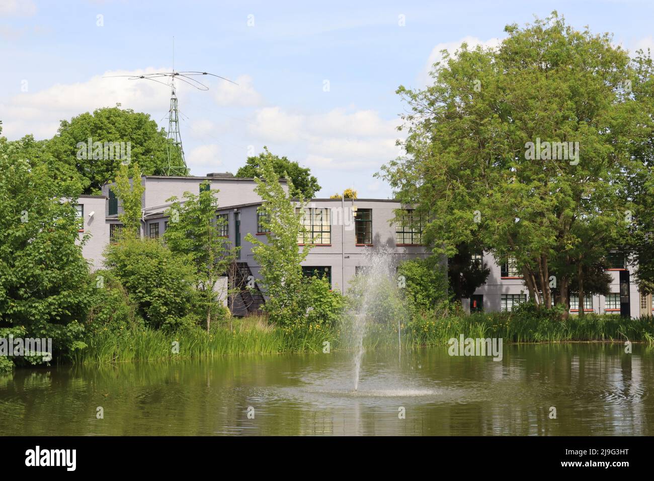 Gli edifici recentemente riverniciati del blocco B a Bletchley Park WWII centro di rottura del codice, Buckinghamshire visto da attraverso il lago Foto Stock