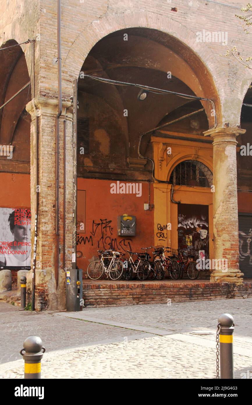 Bologna, Italia. Biciclette parcheggiate sotto il portico di un bel palazzo nel centro storico vandalizzato con vernice spray. Foto Stock