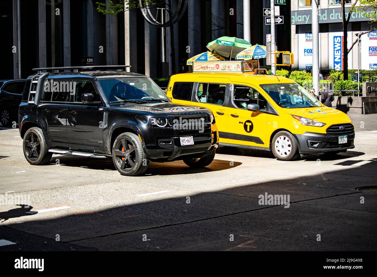 New Land Rover Defender a New York neben einem taxi Yellow Cab Foto Stock
