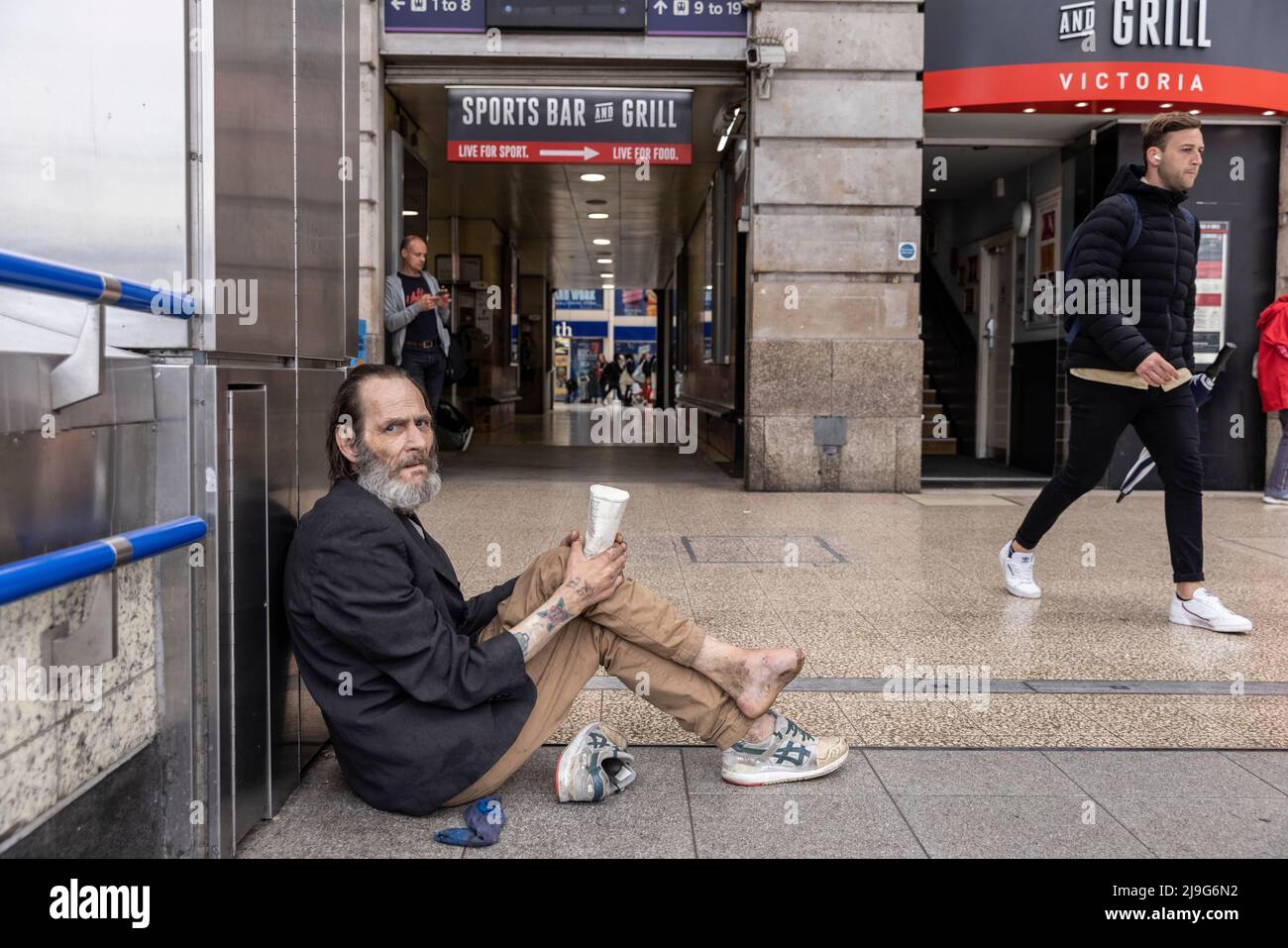 L'uomo senza tetto con il piede infetto sedeva implorando denaro fuori dalla Victoria Station, Londra, Regno Unito Foto Stock