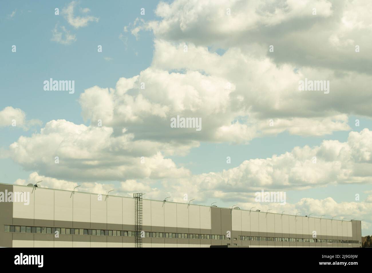 Magazzino e cielo. Edificio grigio. Nuvole sul magazzino. Moderna architettura logistica. Foto Stock