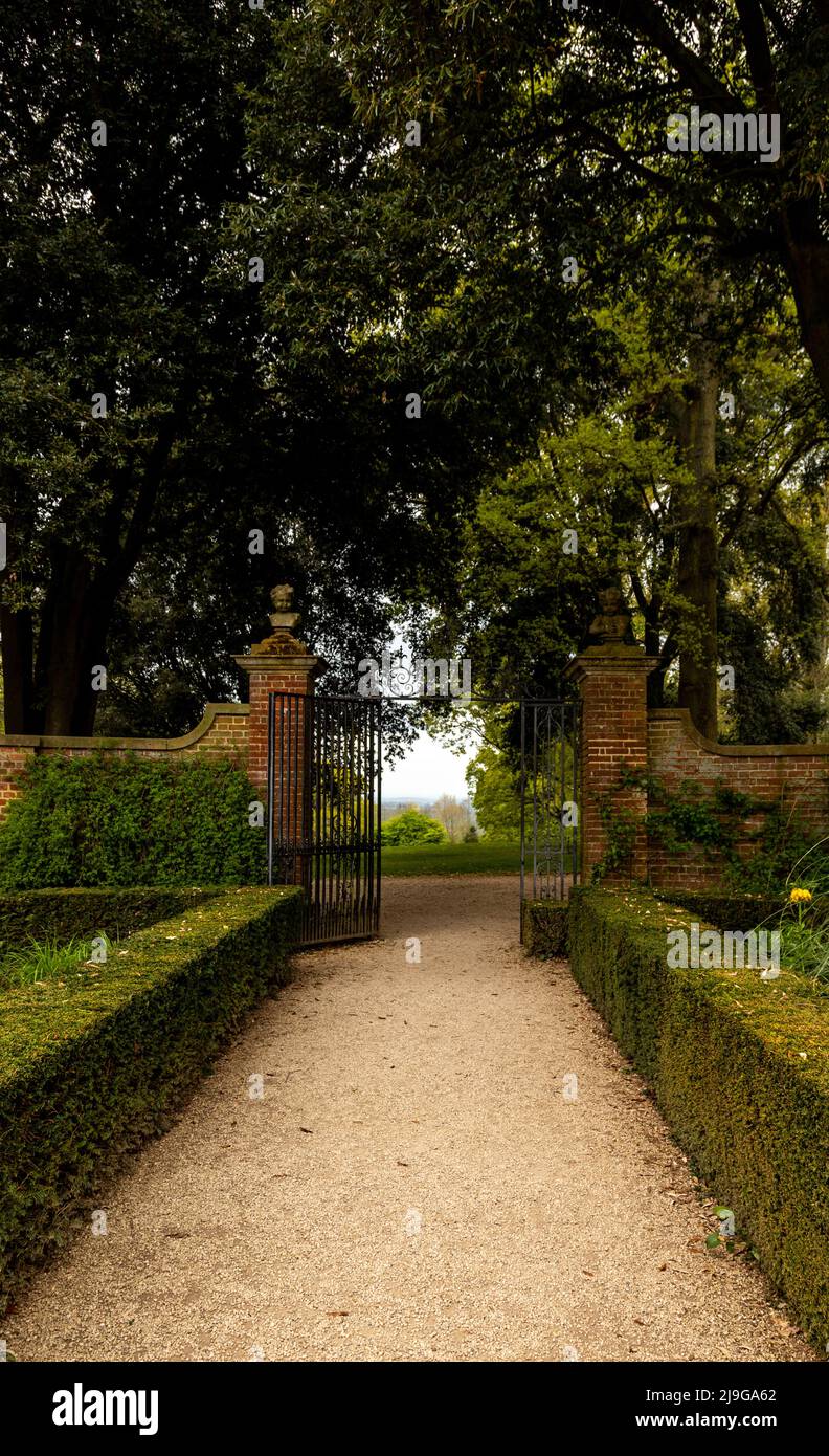 Vista attraverso le porte decorative in ferro battuto da Hidcote Manor Garden, Cotswolds, Chipping Camden, Gloucestershire, Inghilterra, Regno Unito. Foto Stock