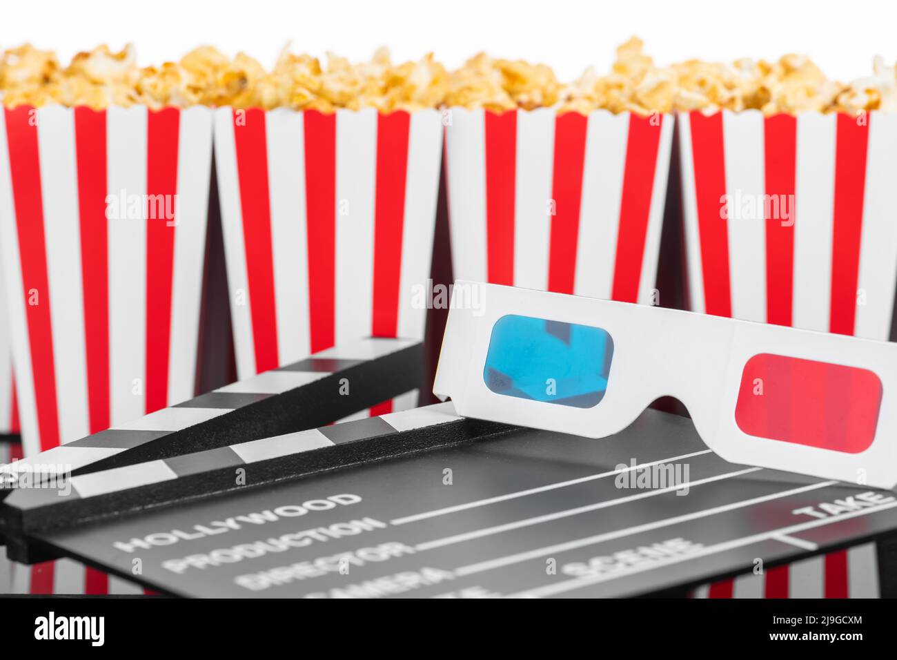 Cinema, film, divertimento e teatro. Scatole di popcorn con strisce bianche e rosse piene di dolce con popcorn al caramello, 3D bicchieri e clapperboard o Foto Stock