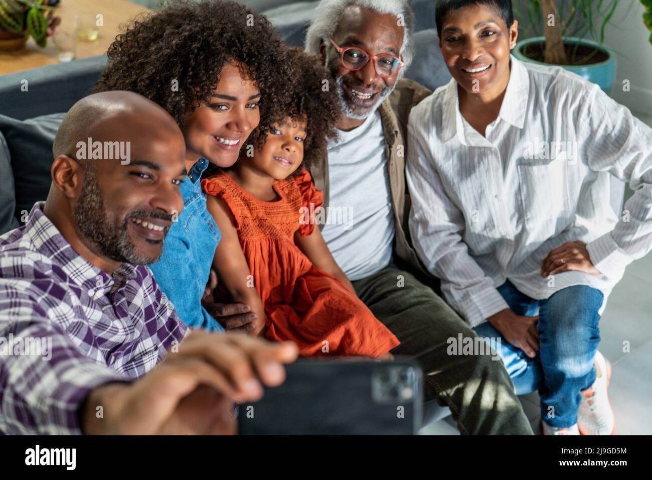 Famiglia felice seduta sul divano mentre prende selfie Foto Stock