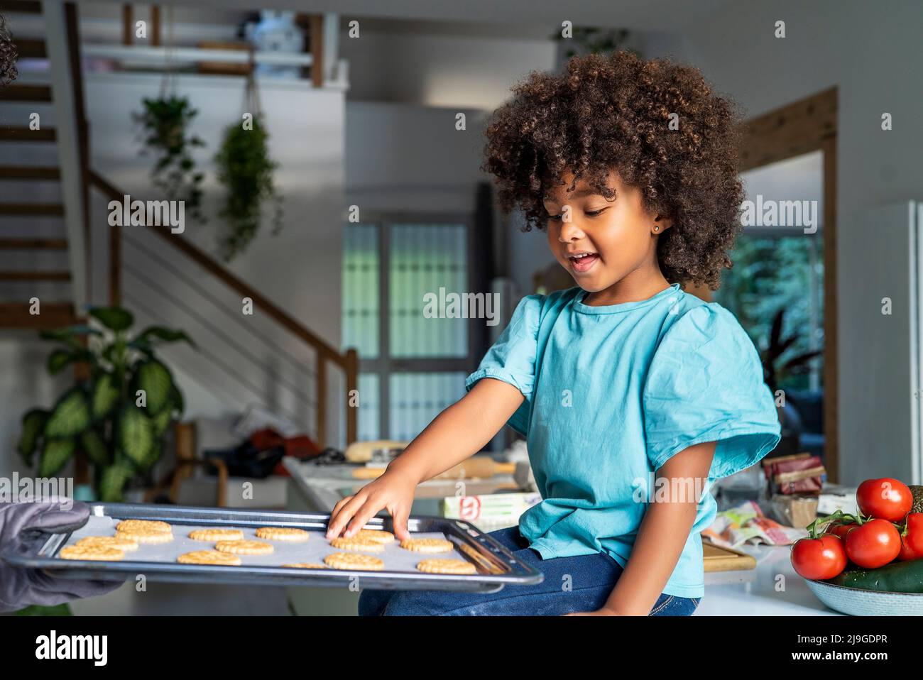Mano della madre che mostra i biscotti cotti al forno della figlia in cucina Foto Stock