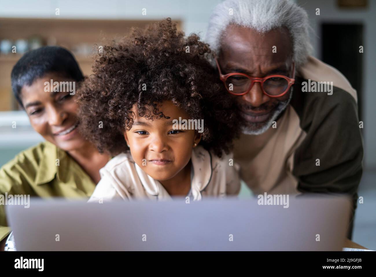 Sorridendo nonni con la nipote usando il laptop Foto Stock