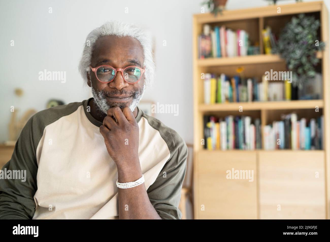 Uomo anziano sorridente seduto in soggiorno Foto Stock