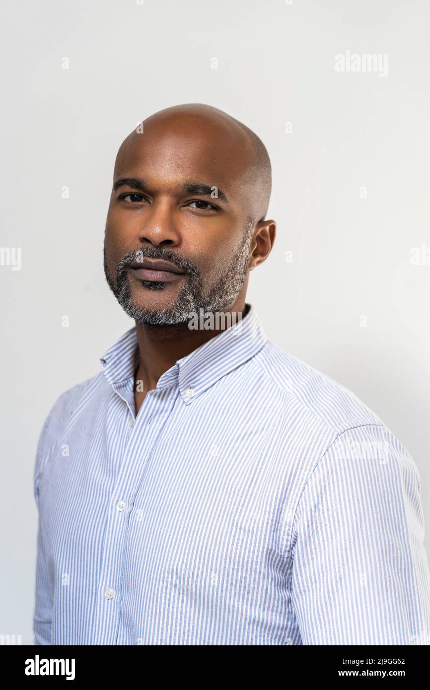 Close-up of smiling man standing against white wall Foto Stock