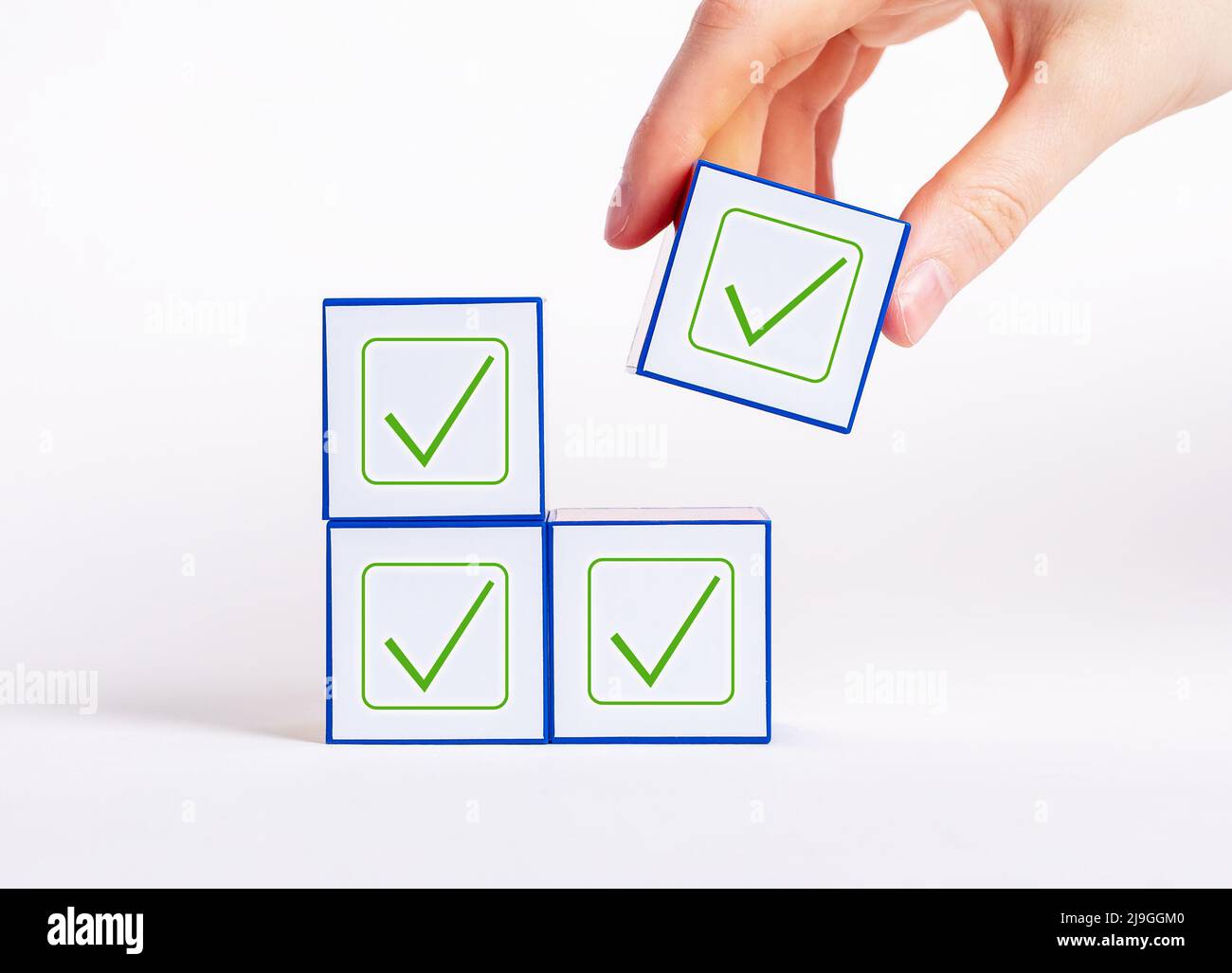 Decisioni affermative all'unanimità. Cubo di tenuta manuale con segno di spunta. Voto, unità nei pensieri, conformismo, concetto di approvazione. Foto di alta qualità Foto Stock
