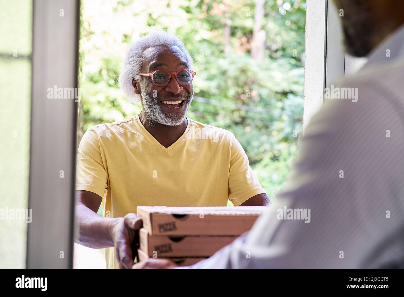 Senior deliveryman consegna pizza a uomo a due passi Foto Stock