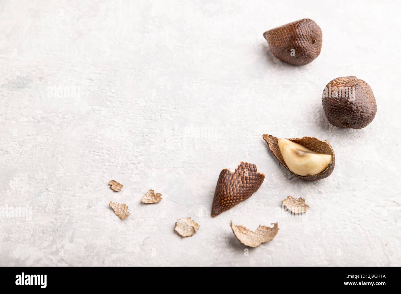 Frutti di Salak o serpente su fondo di cemento grigio. Vista laterale, spazio di copia. Tropicale, cibo sano, estate, esotico, minimalismo. Foto Stock