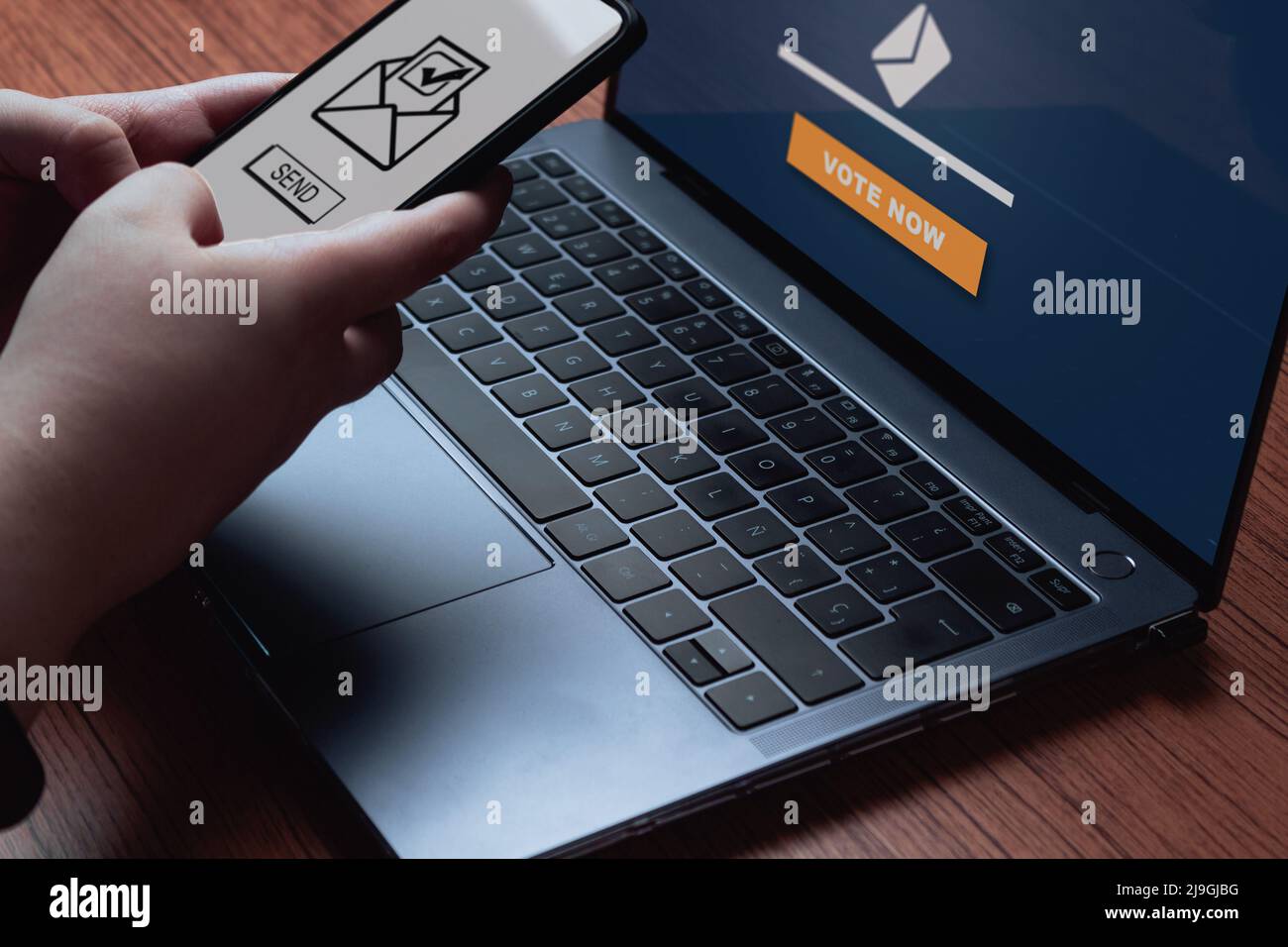 La donna usa un notebook e uno smartphone per votare online. Concetto politico. Votazione elettronica su Internet. Foto Stock