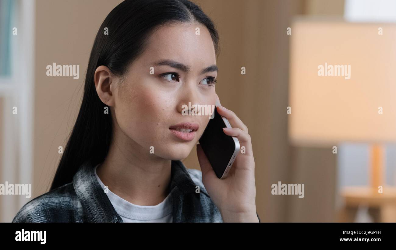 Triste donna asiatica millennial confuso ragazza arrabbiata in casa parlando al telefono rispondere chiamata preoccupazioni circa cattive notizie problemi di rete problemi cellulari Foto Stock