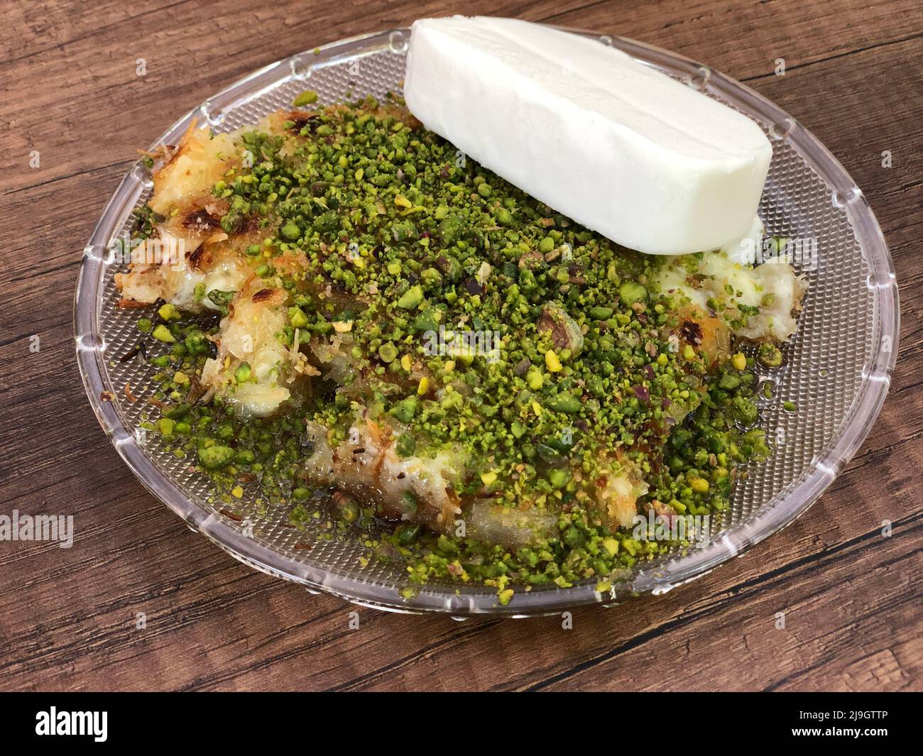 Dessert, tradizionale dessert turco cotto con formaggio all'interno servito con pistacchio e gelato in Turchia. Il cibo dolce turco conosciuto come Kunefe in Tu Foto Stock