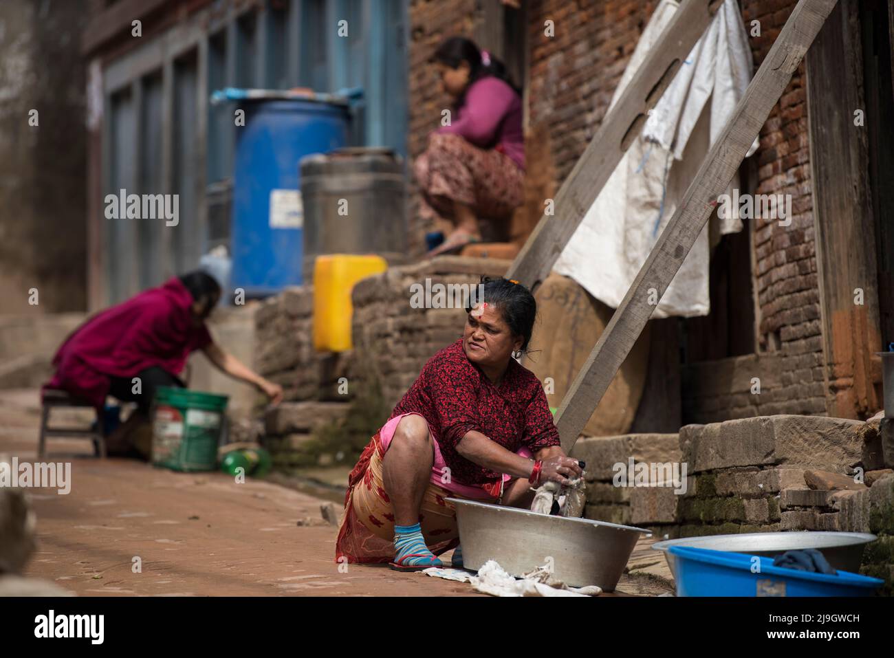 Kathmandu, Nepal- Aprile 20,2022 : le donne lavano vestiti e piatti sulle strade di Piazza Patan Durbar. Foto Stock