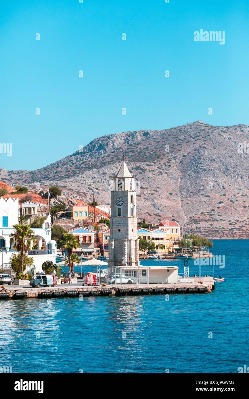 Faro torre orologio sul lungomare della città di Symi sull'isola di Symi, Grecia Foto Stock