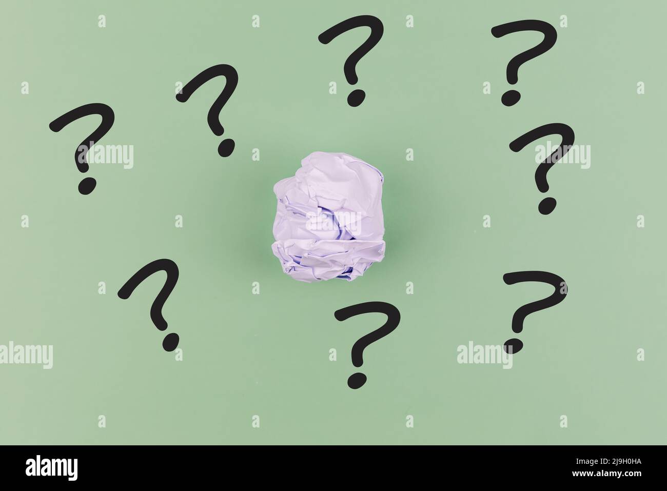 Palla di carta stropicciata con punto interrogativo su sfondo verde Foto Stock