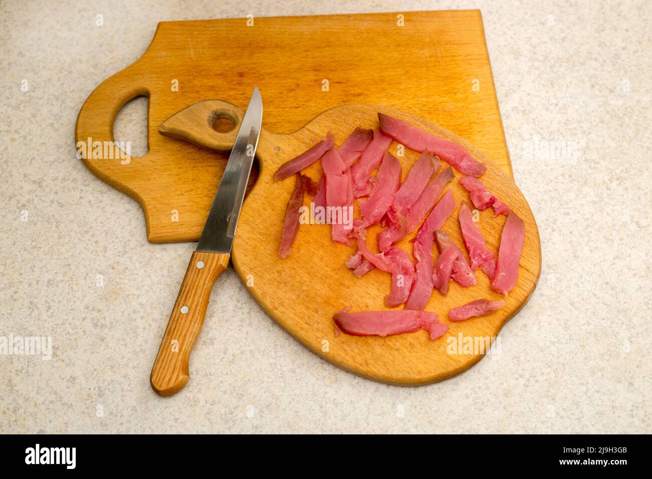 Affettare sul tavolo da cucina fette di tonno freddo Foto Stock