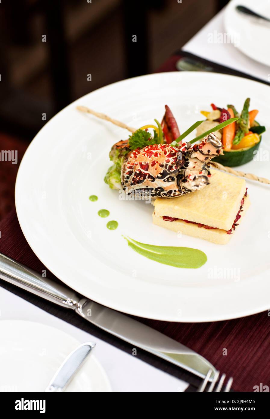 Gratine di aragosta su uno strato di polenta morbida e rosella con un porro buerre blanc, Kayumanis Ubud, Bali, Indonesia. Foto Stock