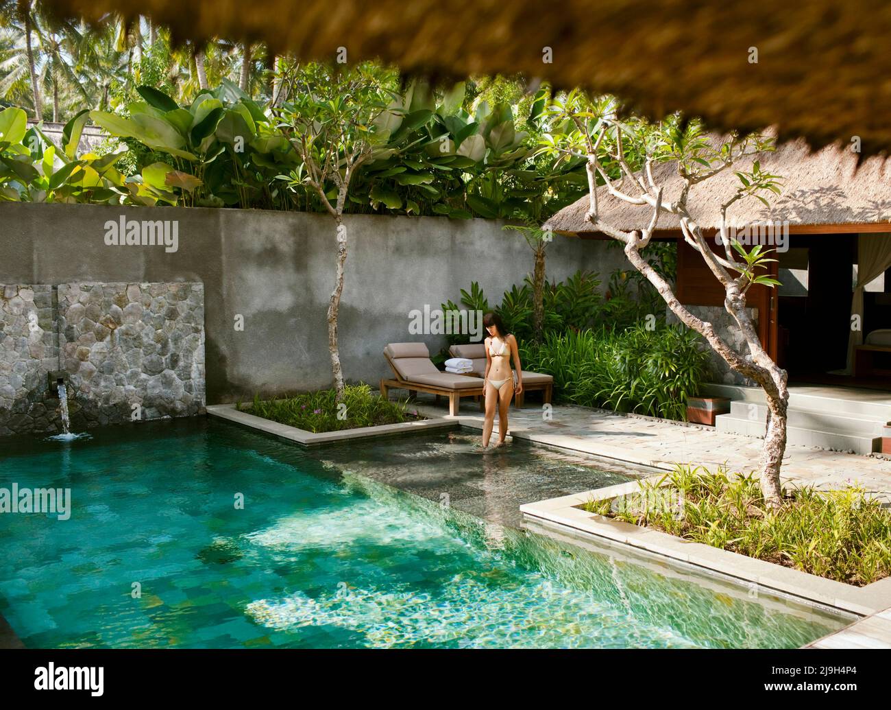 Donna che entra nella piscina di Bile Deluxe Pool Villa, una villa con piscina privata a Kayumanis Ubud, Bali, Indonesia. Foto Stock