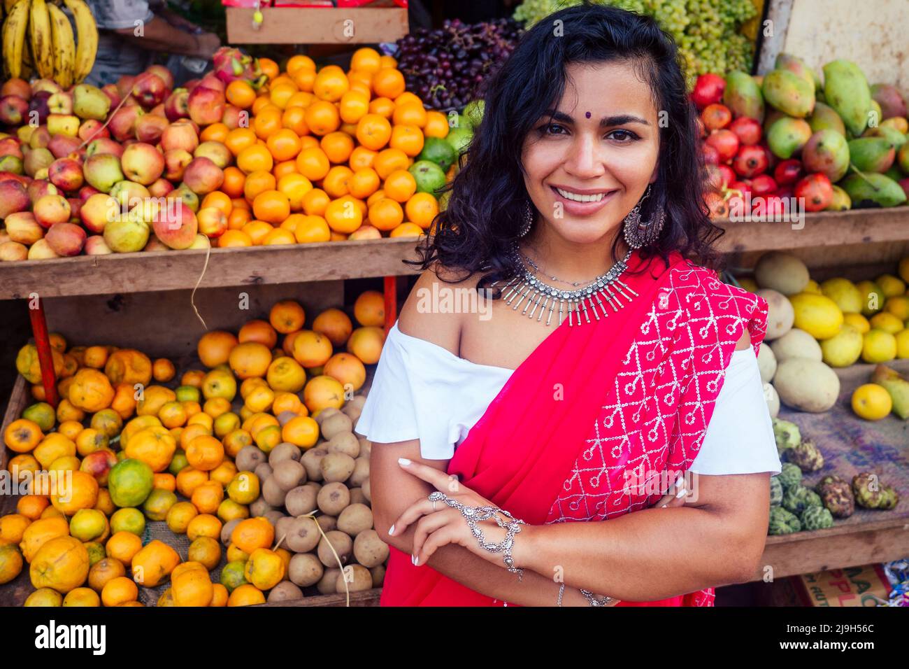 Ritratto di bella tradizionale indiano venditore business donna in rosso sari vestito con cliente in strada Delhi mercato india mumbai.Happy ragazza shopper Foto Stock