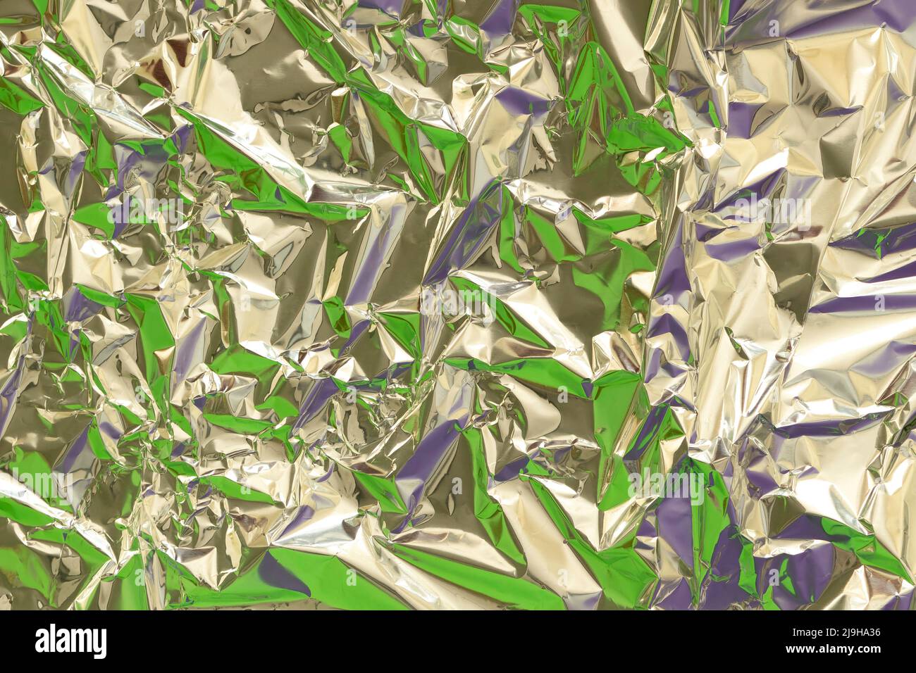 Astratto argento alluminio rugoso foglio multicolore sfondo tessuto riflettente verde e viola luce. Lucentezza metallizzata in lamina argentata Foto Stock