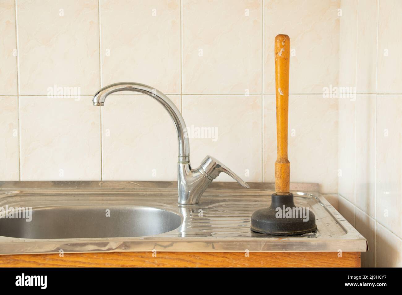Lo stantuffo si trova nel lavandino in cucina, pulendo i tubi ostruiti, un vecchio stantuffo per pulire i tubi Foto Stock