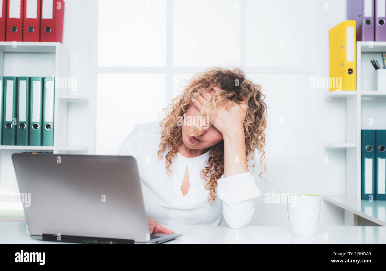 Stanco lavoratore d'ufficio. Donna pigra annoiata che usa il computer portatile la mattina, noiosa in ufficio. Foto Stock