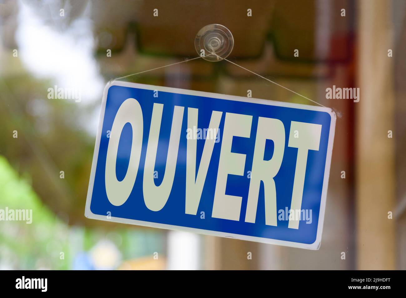 Primo piano su un segno blu nella finestra di un negozio che visualizza il messaggio in francese - Ouvert - significato in inglese - aperto -. Foto Stock