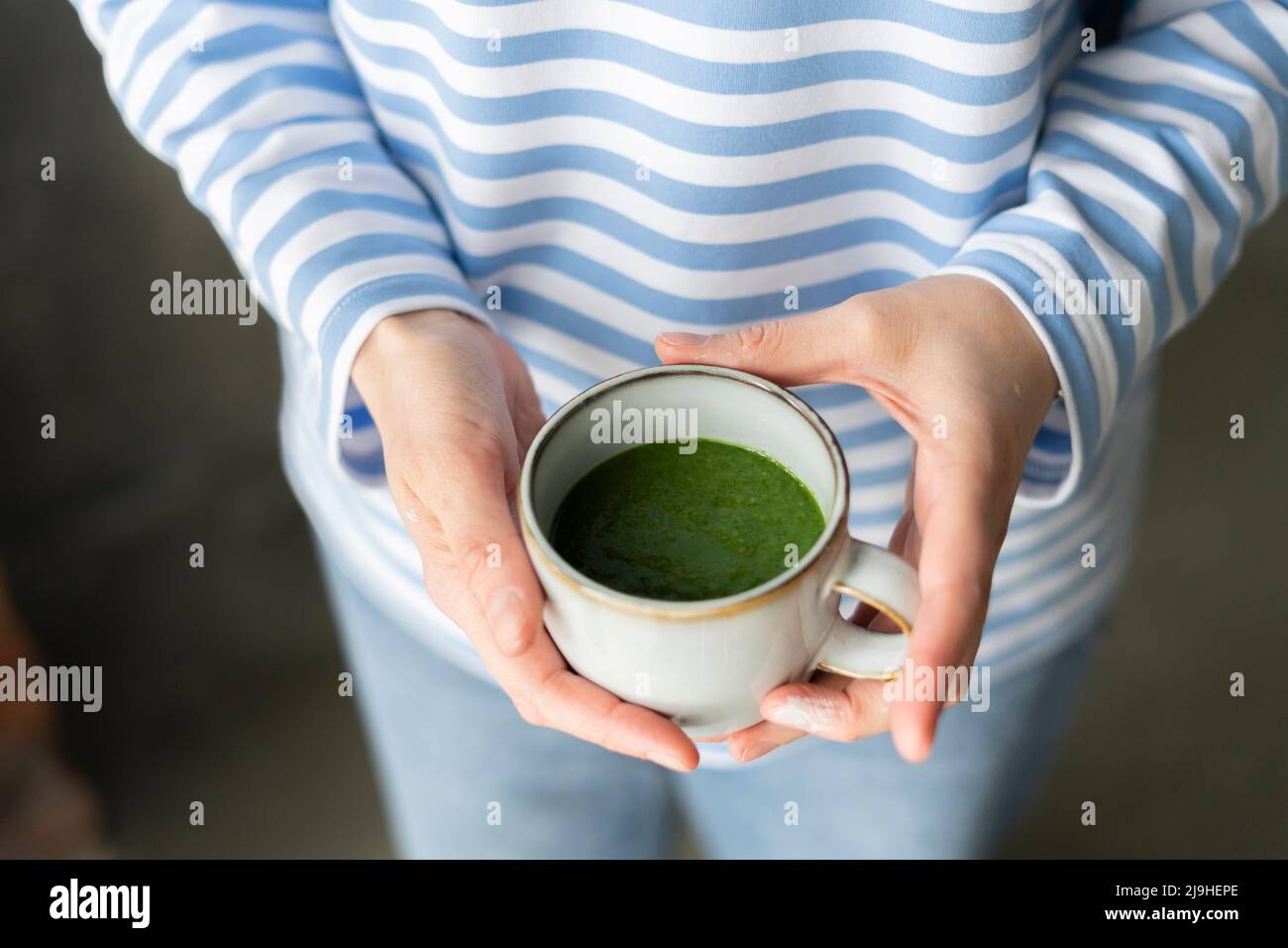 Mani di donna che tengono una tazza di tè verde Foto Stock