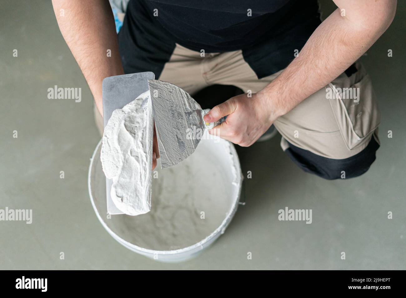 Uomo con attrezzatura da lavoro e intonaco a casa Foto Stock