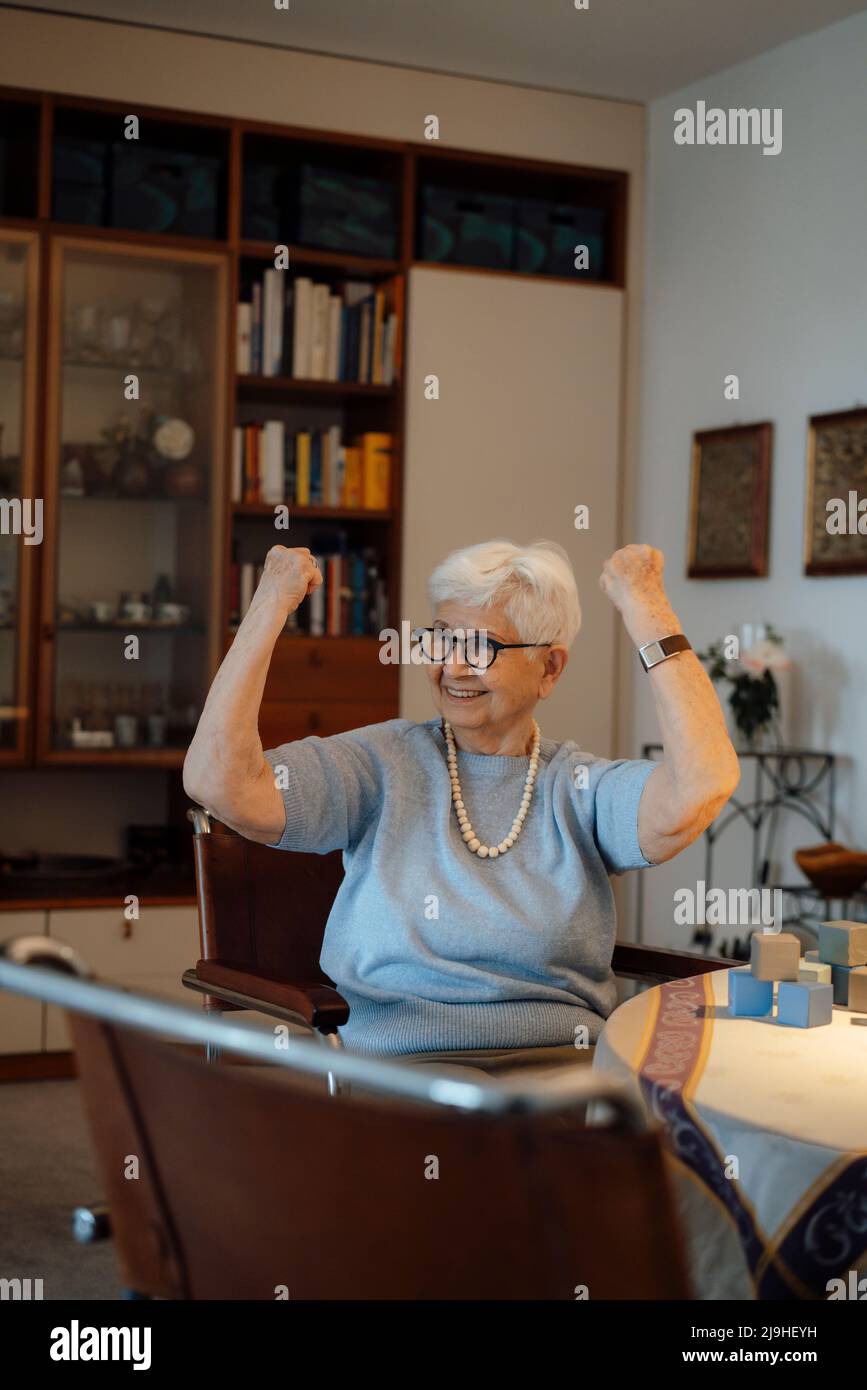 Donna anziana felice godendo blocco giocattolo a casa Foto Stock
