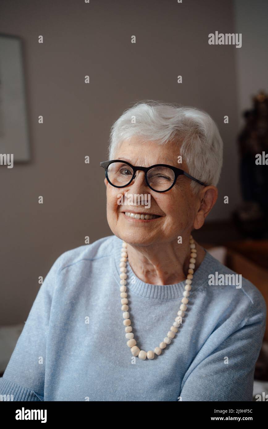 Donna anziana felice che indossa occhiali che vagliano a casa Foto Stock