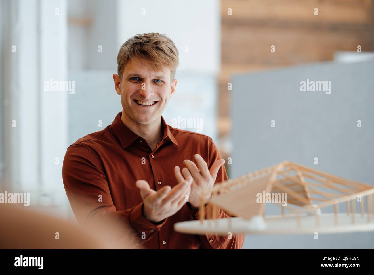 Felice uomo d'affari gesturing con modello a forma di foglia in ufficio Foto Stock