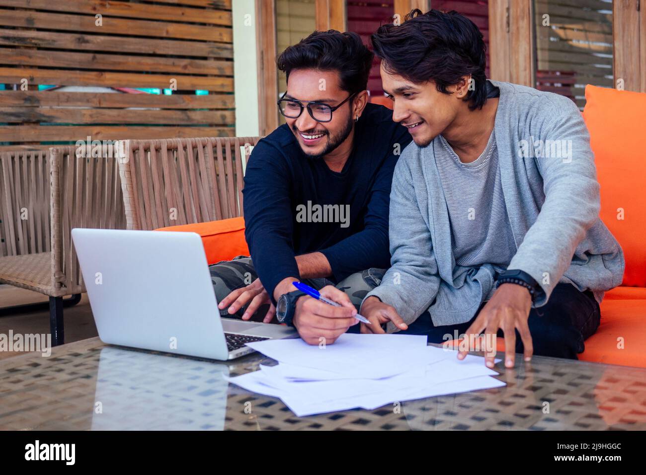 Indian giovani uomini d'affari gente freelance di lavoro all'aperto chaise lounge sulla spiaggia con laptop.Two amici di successo freelancing surf Foto Stock