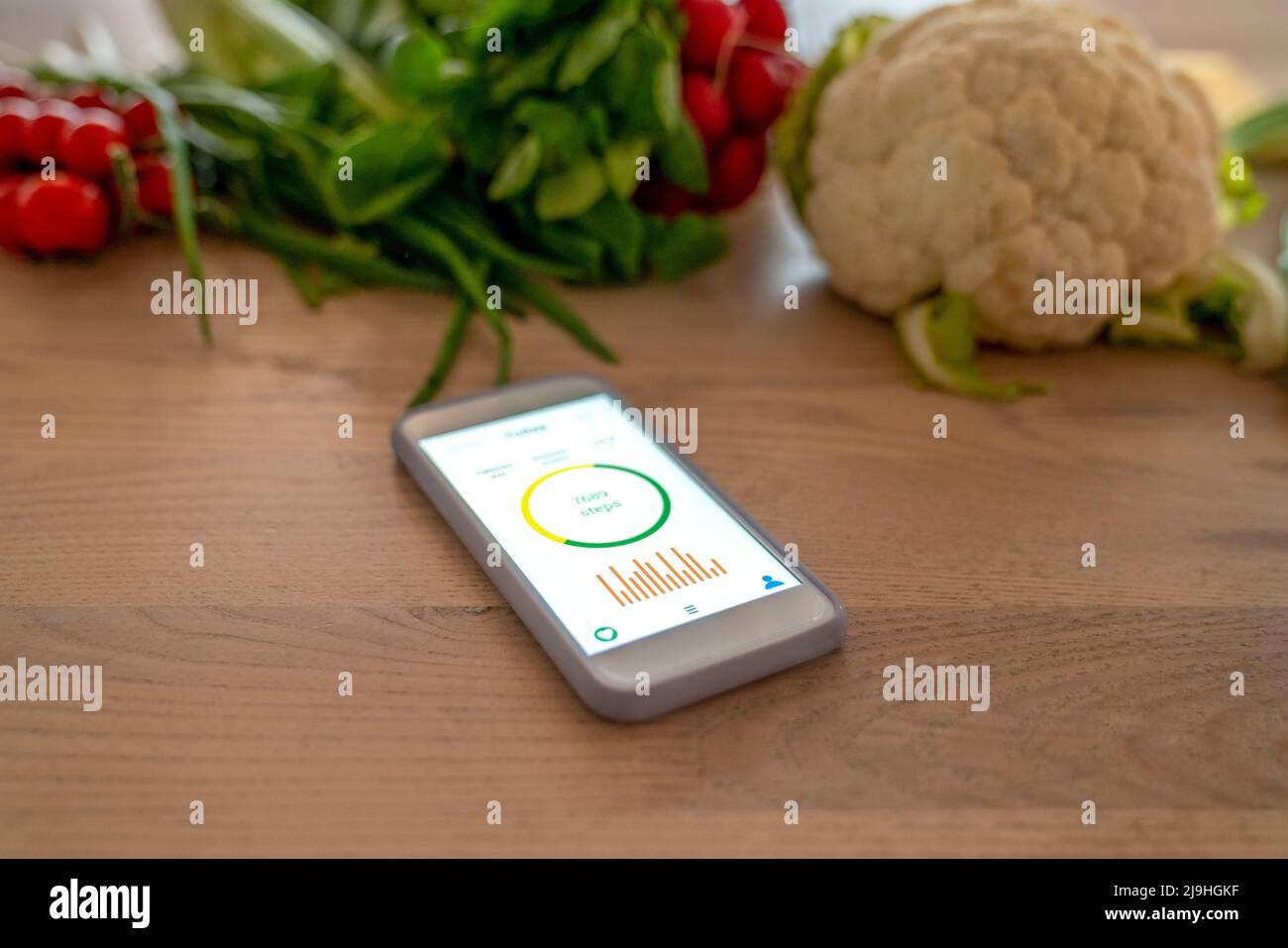 Smartphone con Health tracker sullo schermo del dispositivo dalle verdure Foto Stock