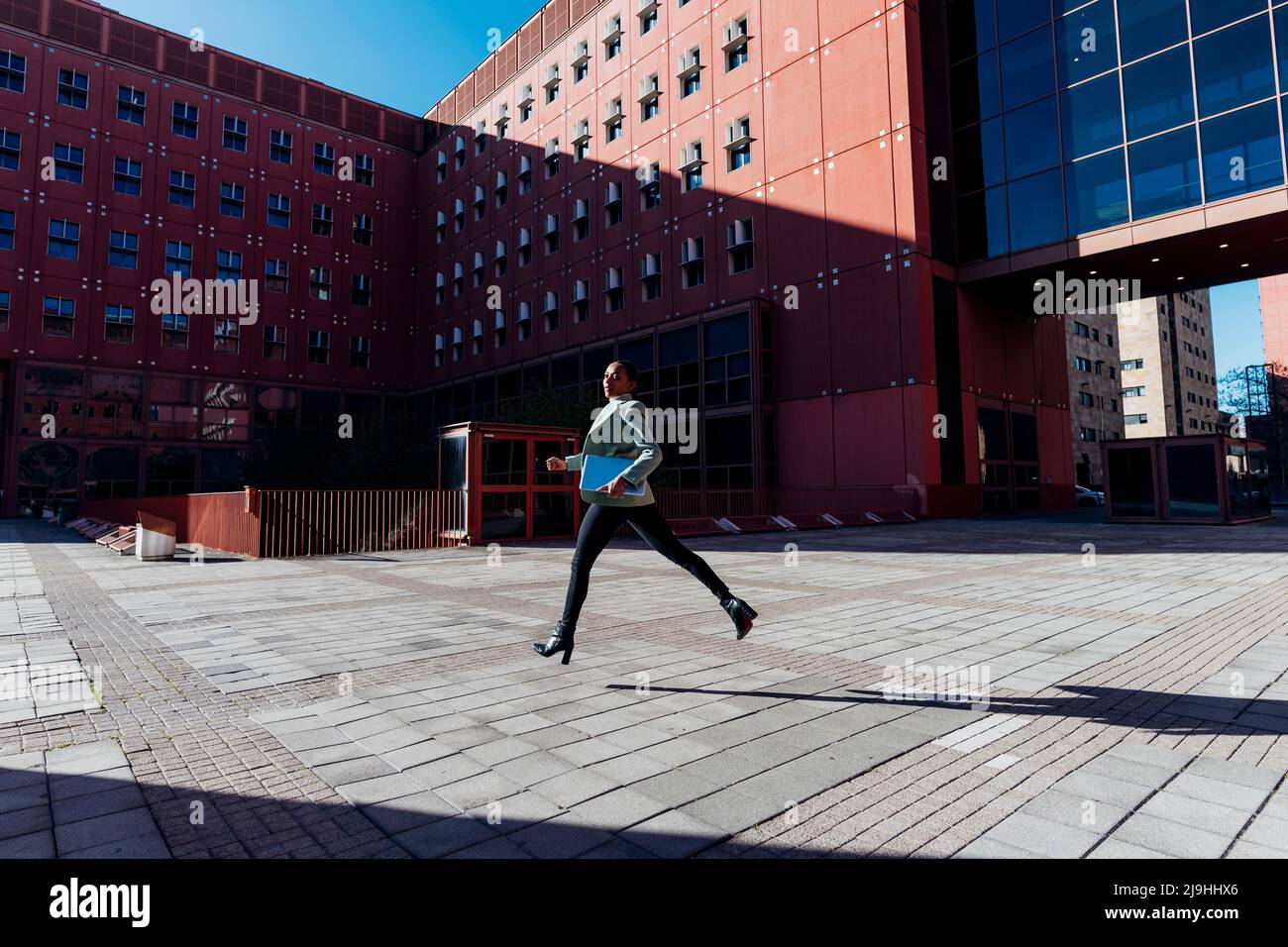 Giovane donna d'affari che corre tardi per lavoro in giornata di sole Foto Stock