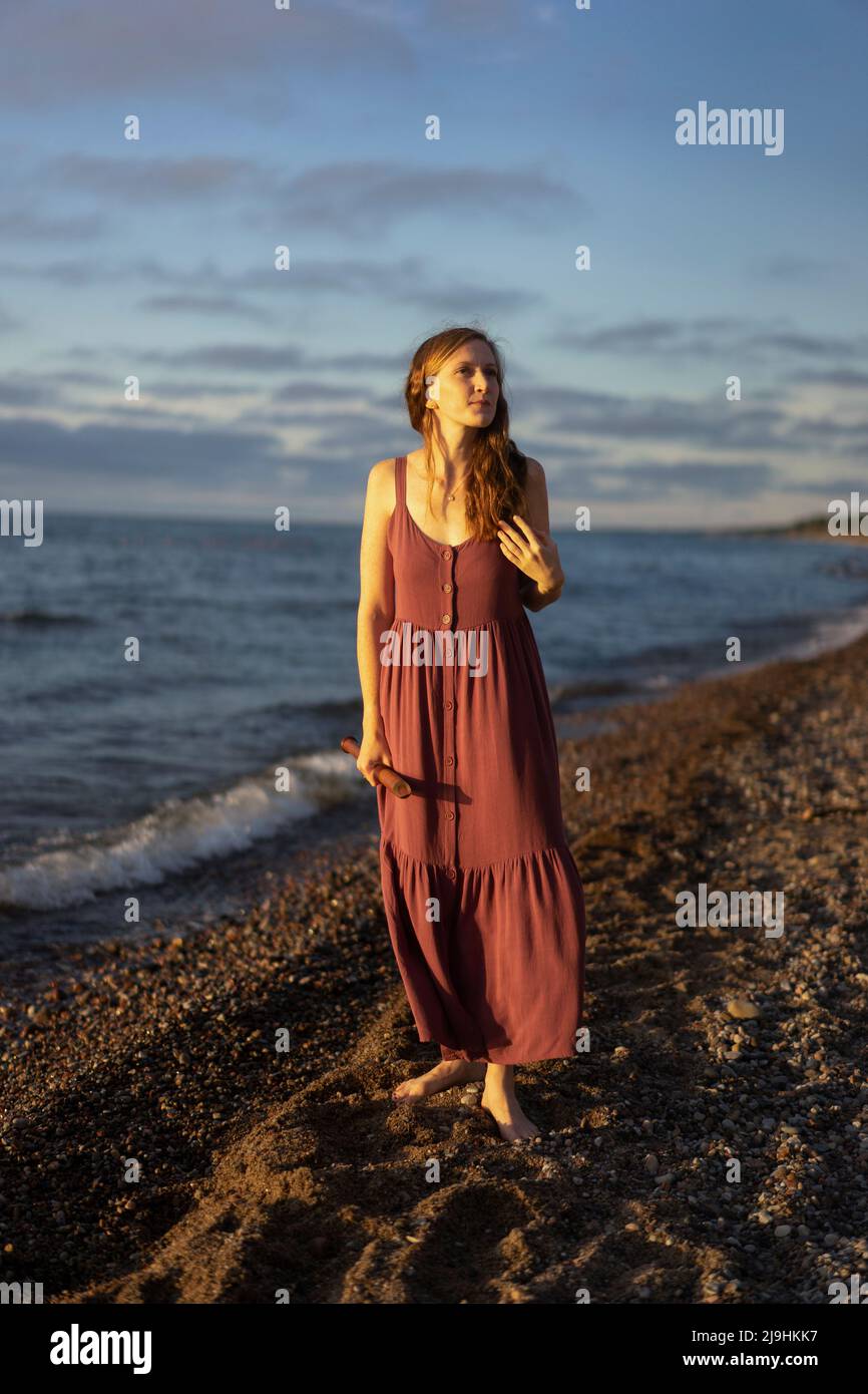 Donna che tiene flauto in piedi in spiaggia Foto Stock
