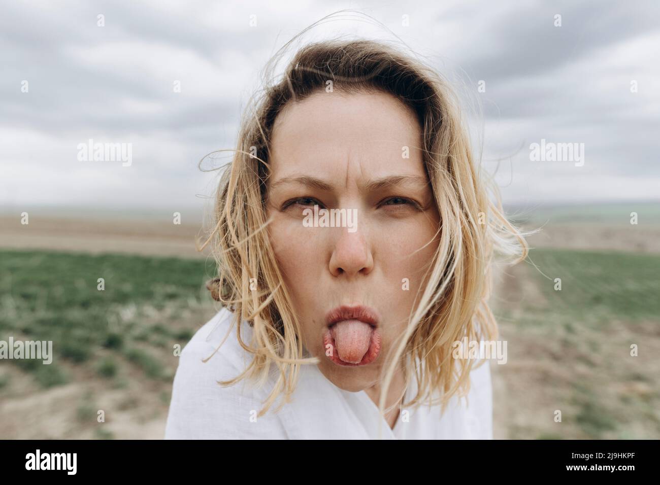 Donna giocosa che attacca la lingua al campo agricolo Foto Stock