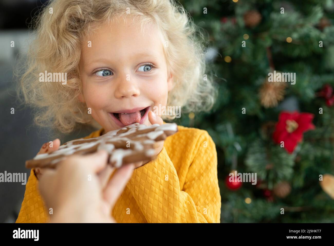 Felice ragazza bionda che mangia pan di zenzero a casa Foto Stock